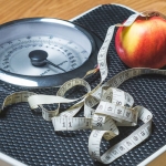 Measuring tape and apple on scale